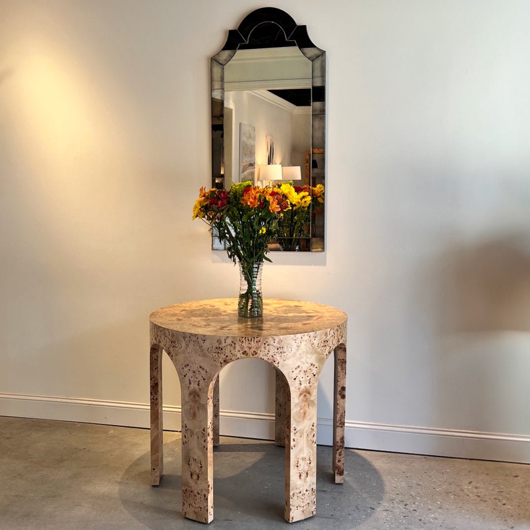 Mirror hangs above ornate table, interior setting visible.