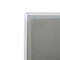 Headboard close-up, gray upholstery with white trim.
