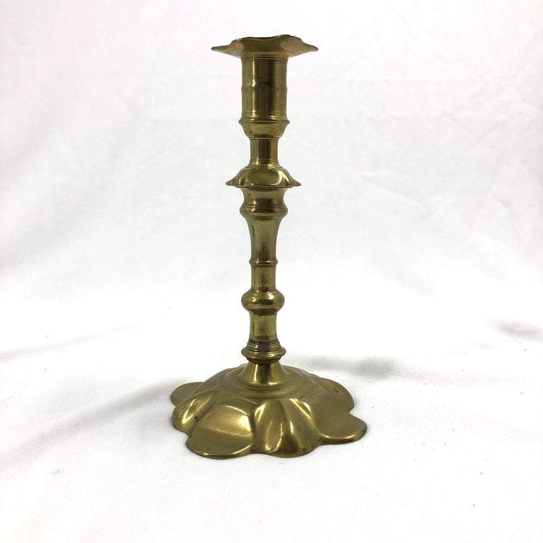 Single Queen Anne brass candlestick on white background.
