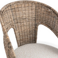 Close-up of the curved rattan back and open arms above the cream cushion