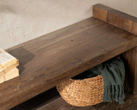 Elevated detail of the reclaimed wood bench seat with books at one end and a basket tucked underneath