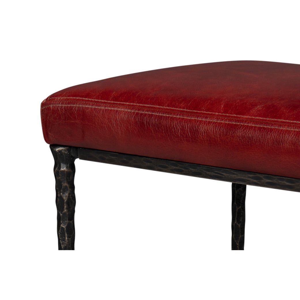 Close-up of red leather seat's corner on rustic bench.