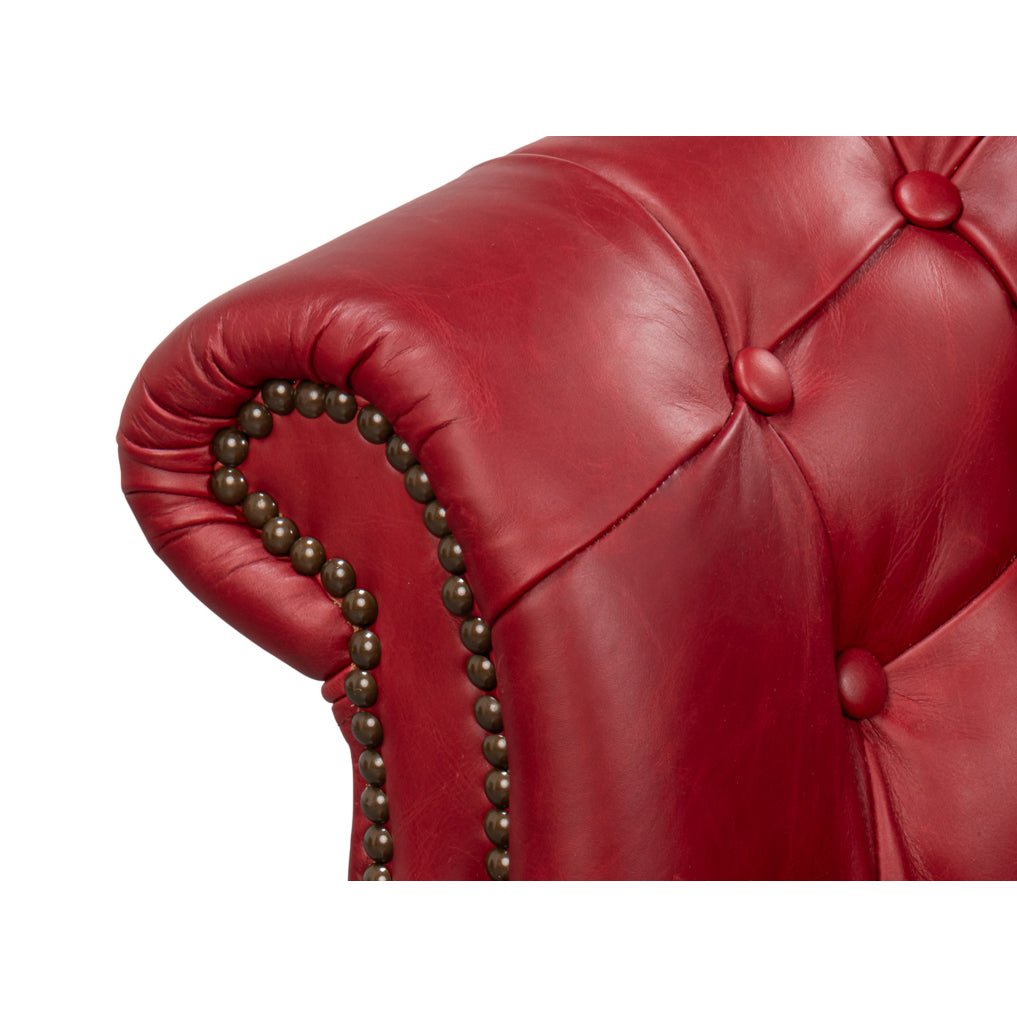 Red leather chair armrest with nailhead trim detail.