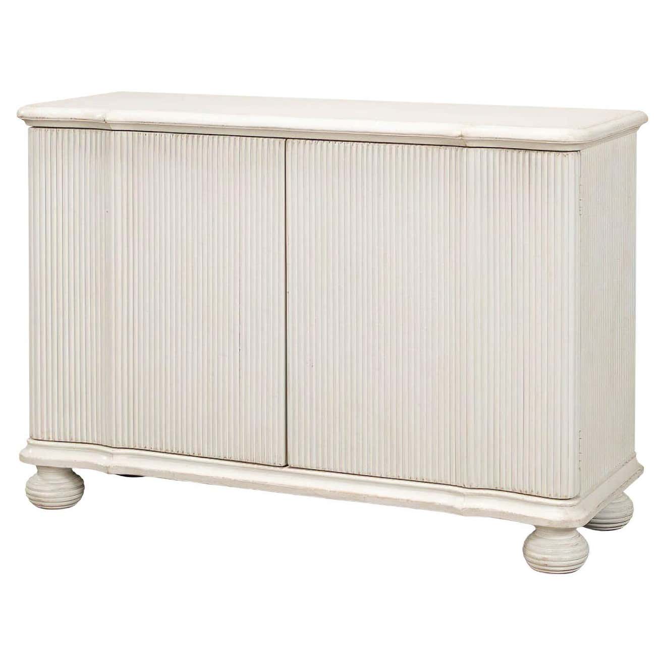 Reeded antique white cabinet angled view with closed doors.