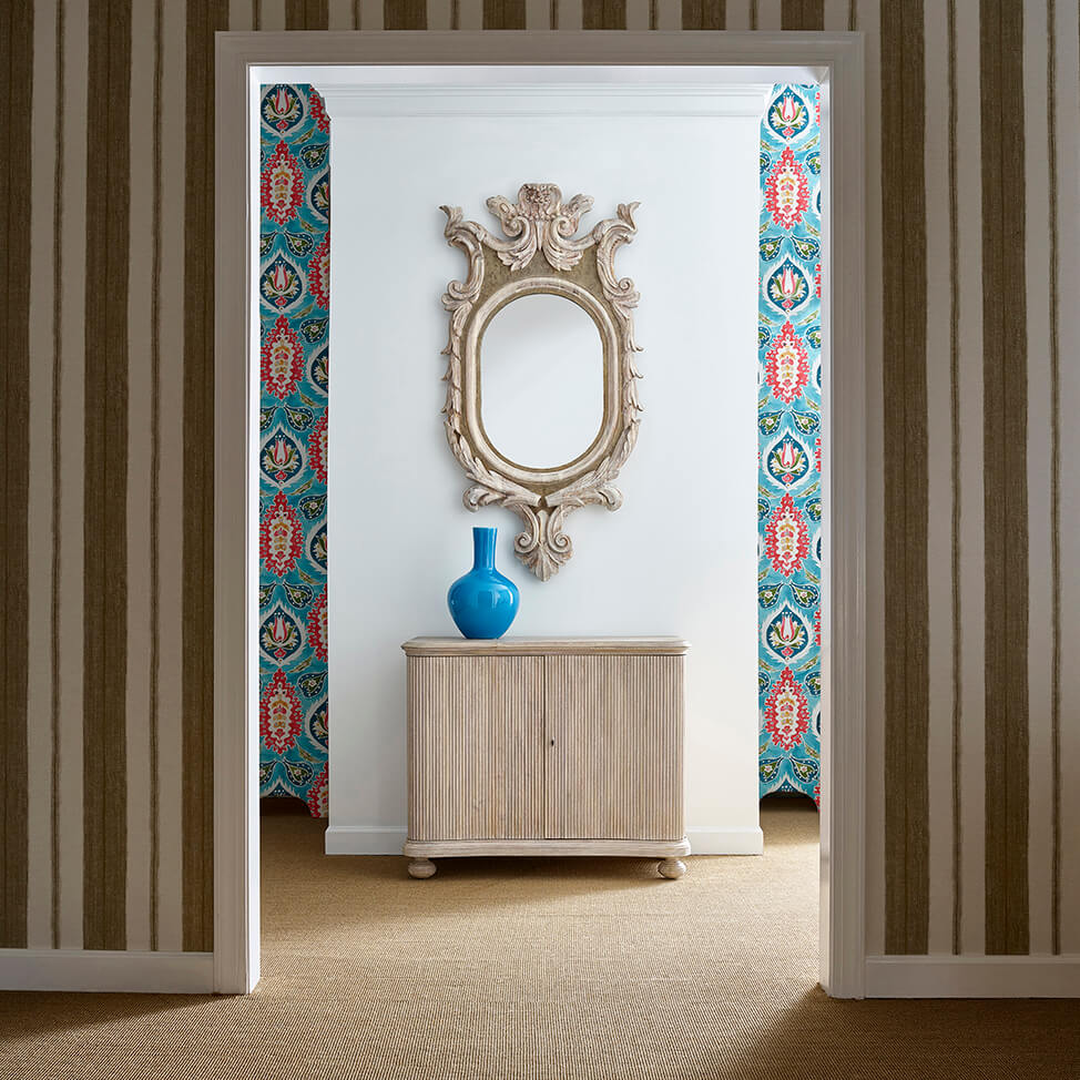 Reeded cabinet in room setting, beneath ornate mirror.