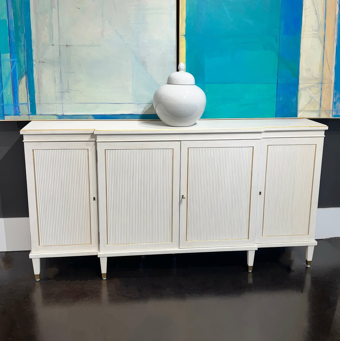 Regency credenza with white vase, blue abstract artwork background.
