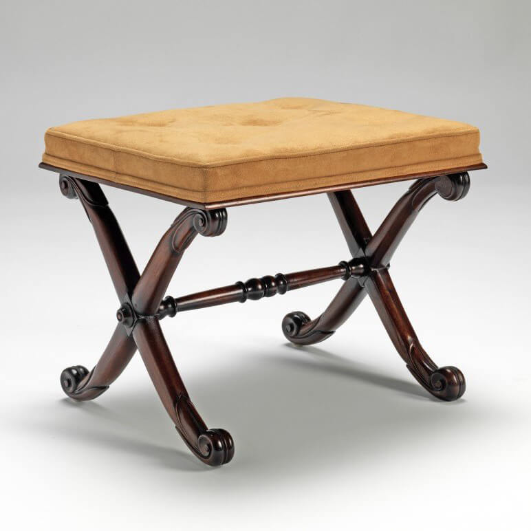 Regency stool with carved mahogany X frame, angled view.