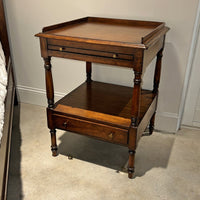 Regency style side table next to bed, angled view.