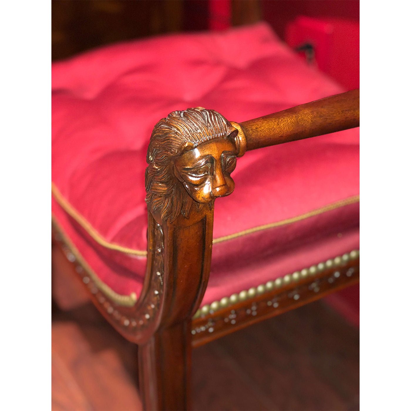 Armchair lion carving close-up, red cushion with trim.