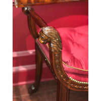 Close-up of armchair lion carving, red cushion detail.