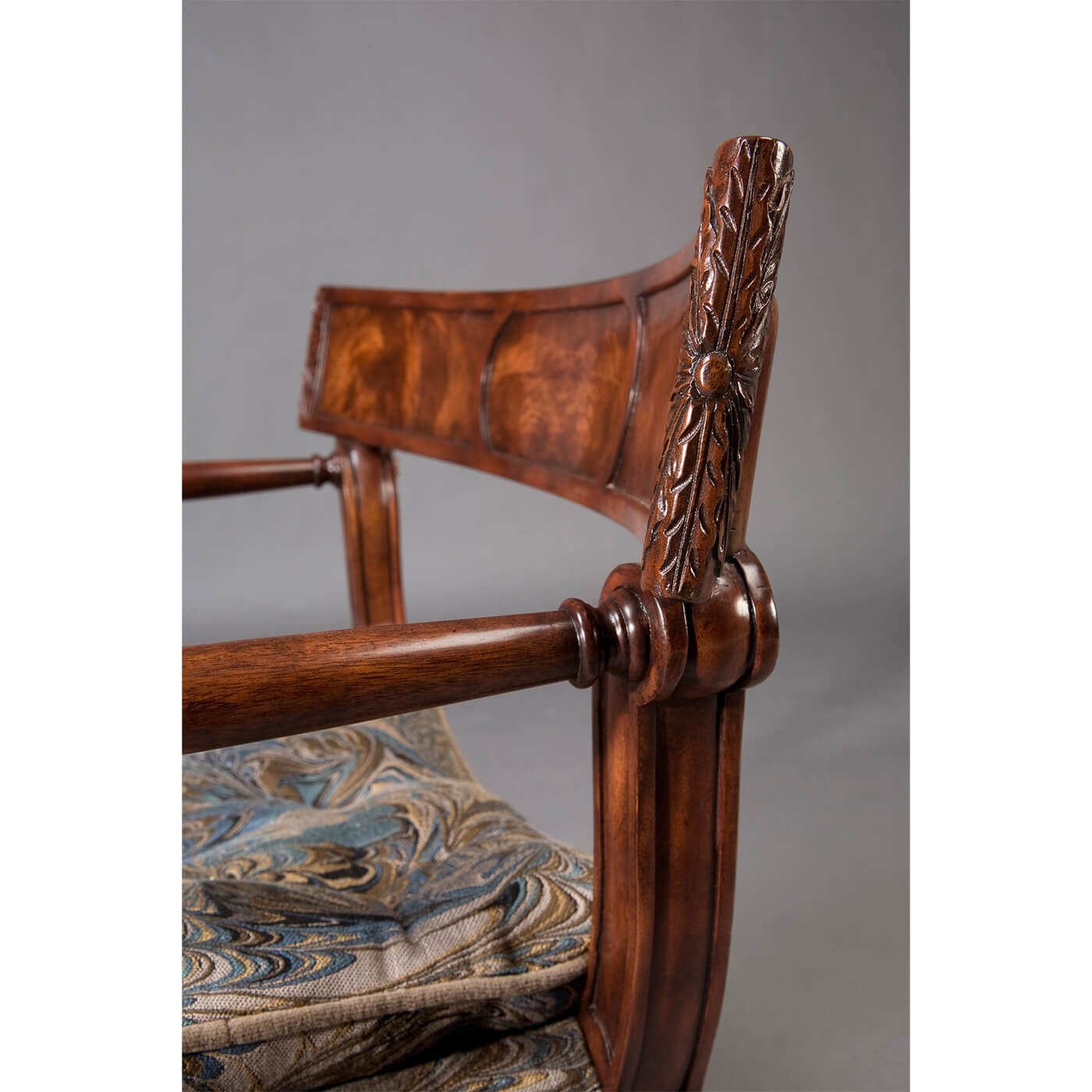 Close-up of Regency armchair backrest, blue pattern cushion.