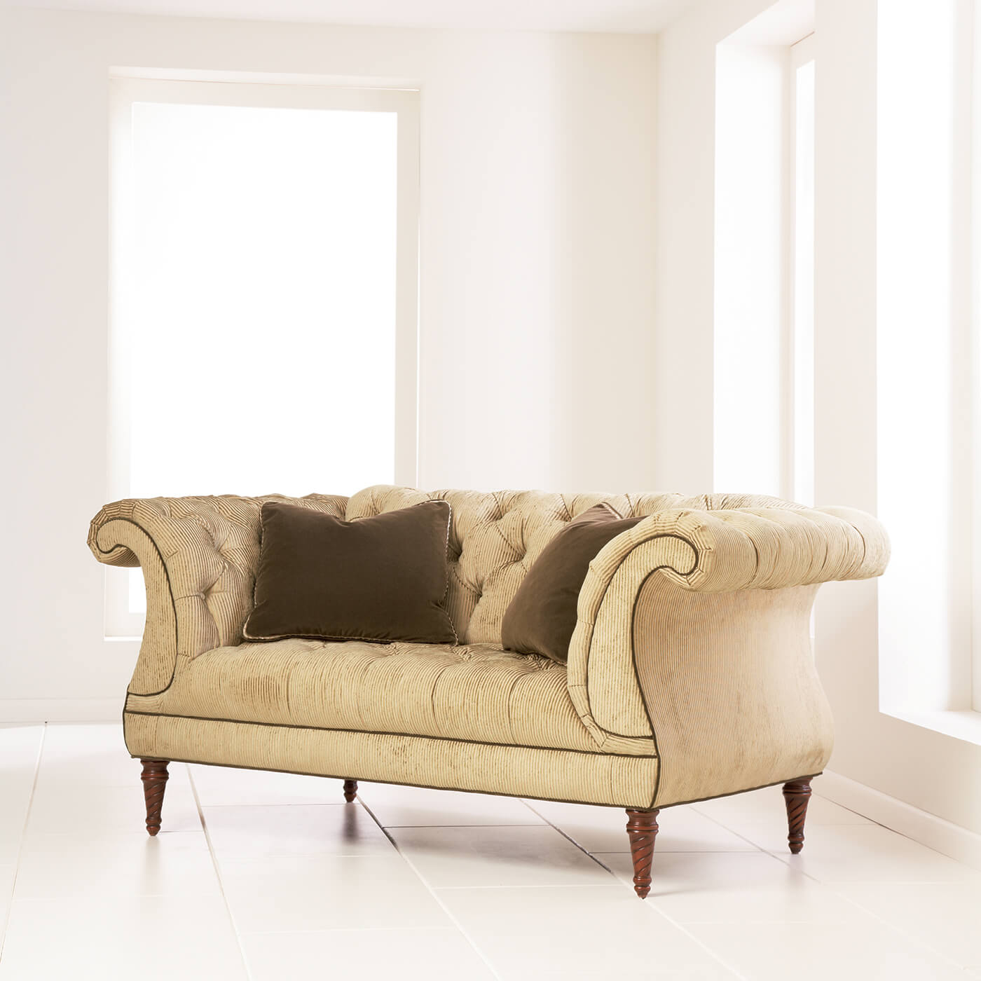 Beige tufted lyre sofa with brown pillows in white room.