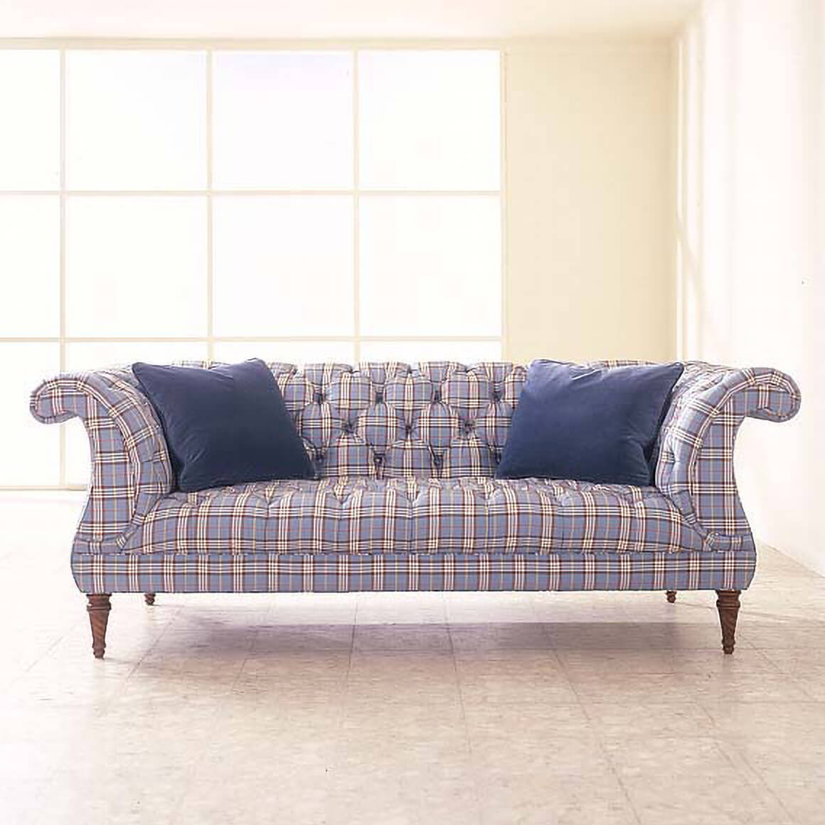 Blue plaid tufted lyre sofa with navy pillows.