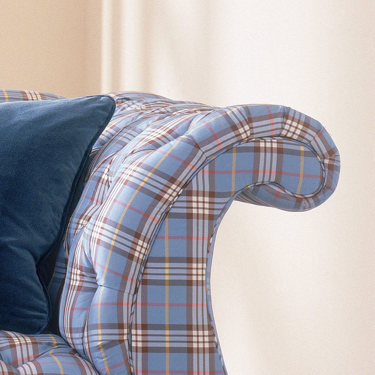 Close-up of blue plaid tufted lyre sofa arm.