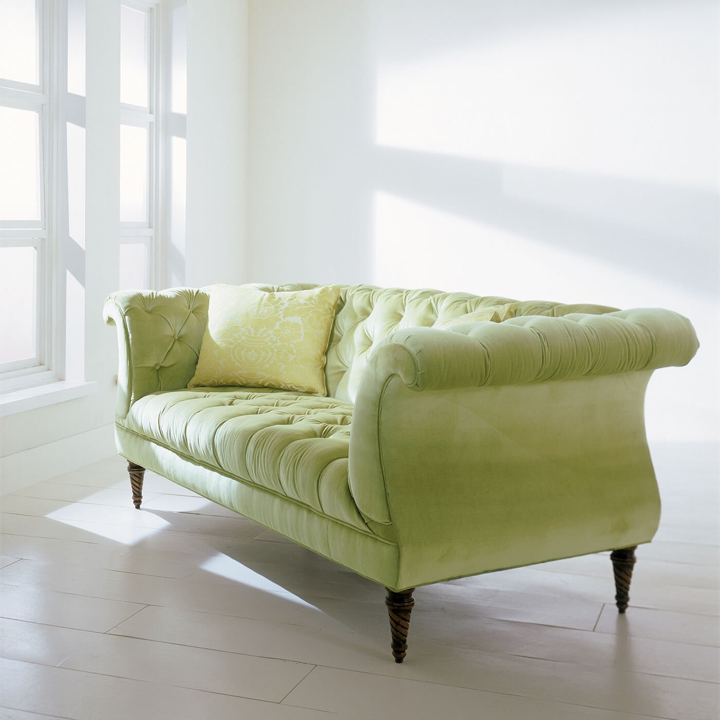 Green tufted lyre sofa with light green pillow.