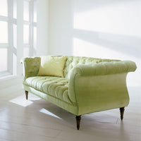 Green tufted lyre sofa with light green pillow.