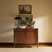 Regency style cabinet staged with decor, wall paintings above.