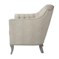Light upholstered tufted chair, side view featuring curved profile.
