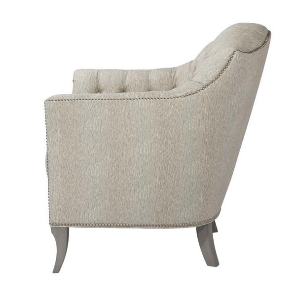 Light upholstered tufted chair, side view featuring curved profile.