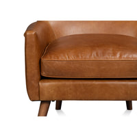 Close-up cushion detail of brown leather wingback chair seat.