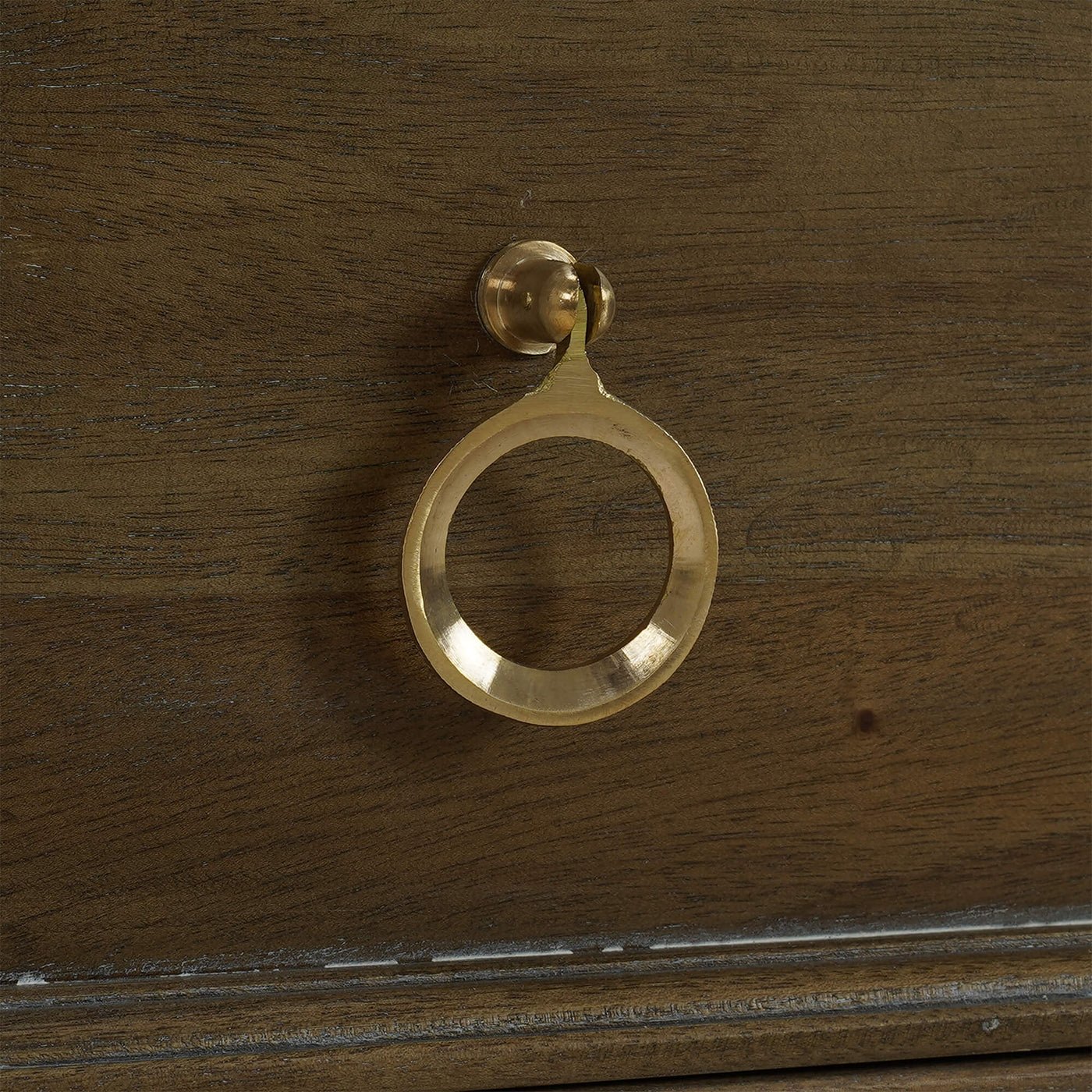 Brass handle on rustic commode drawer, close-up.