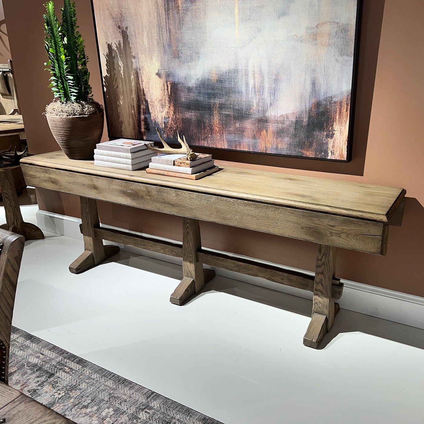 Rustic oak hunt table styled with decor in showroom.