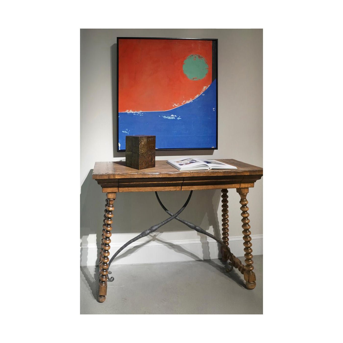 Console table styled with decor, artwork above, indoor setting.