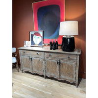 Sideboard styled with lamp and art in dark room.