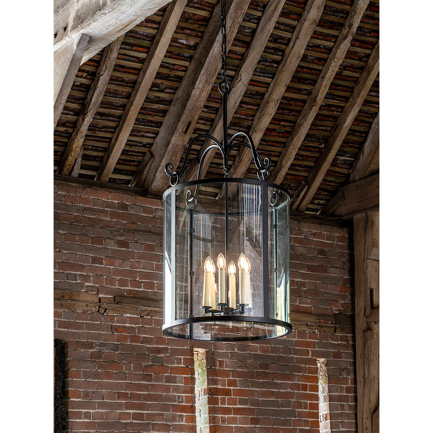 Lit rustic hall lantern hanging in brick interior.