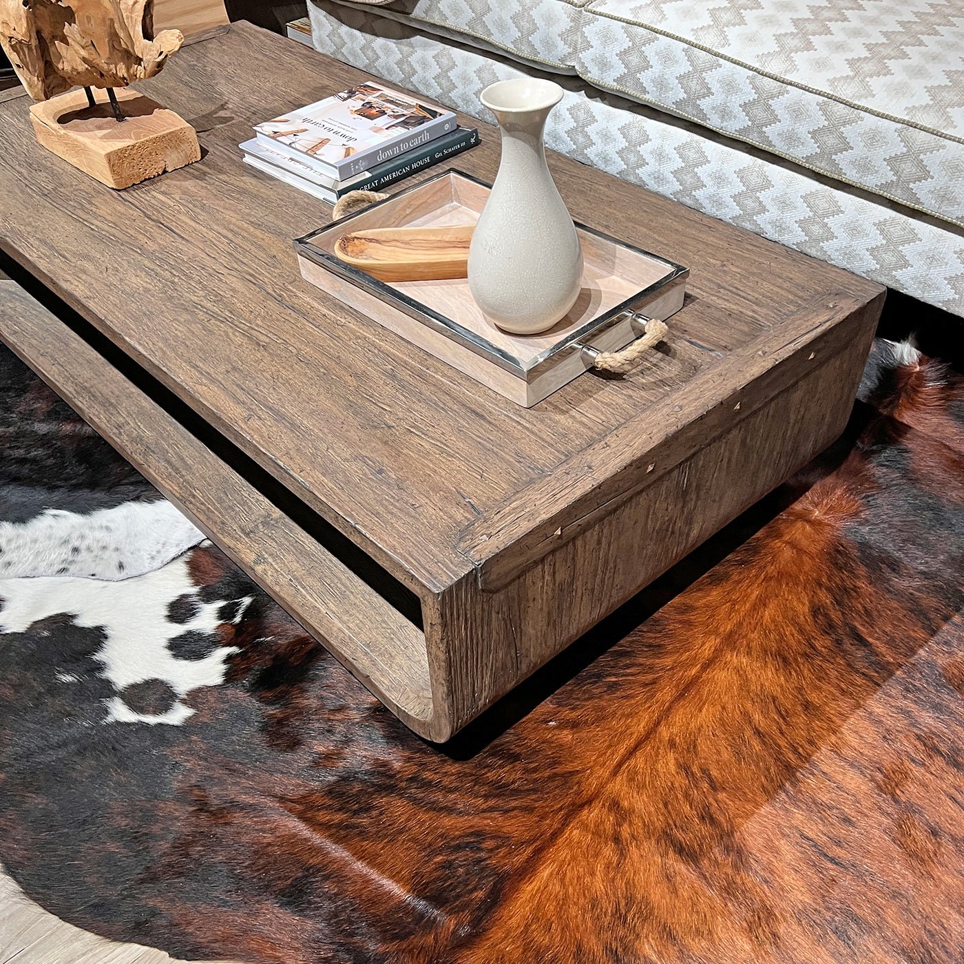 Rustic table styled with books and vase on cowhide rug.