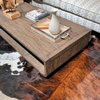 Rustic table styled with books and vase on cowhide rug.