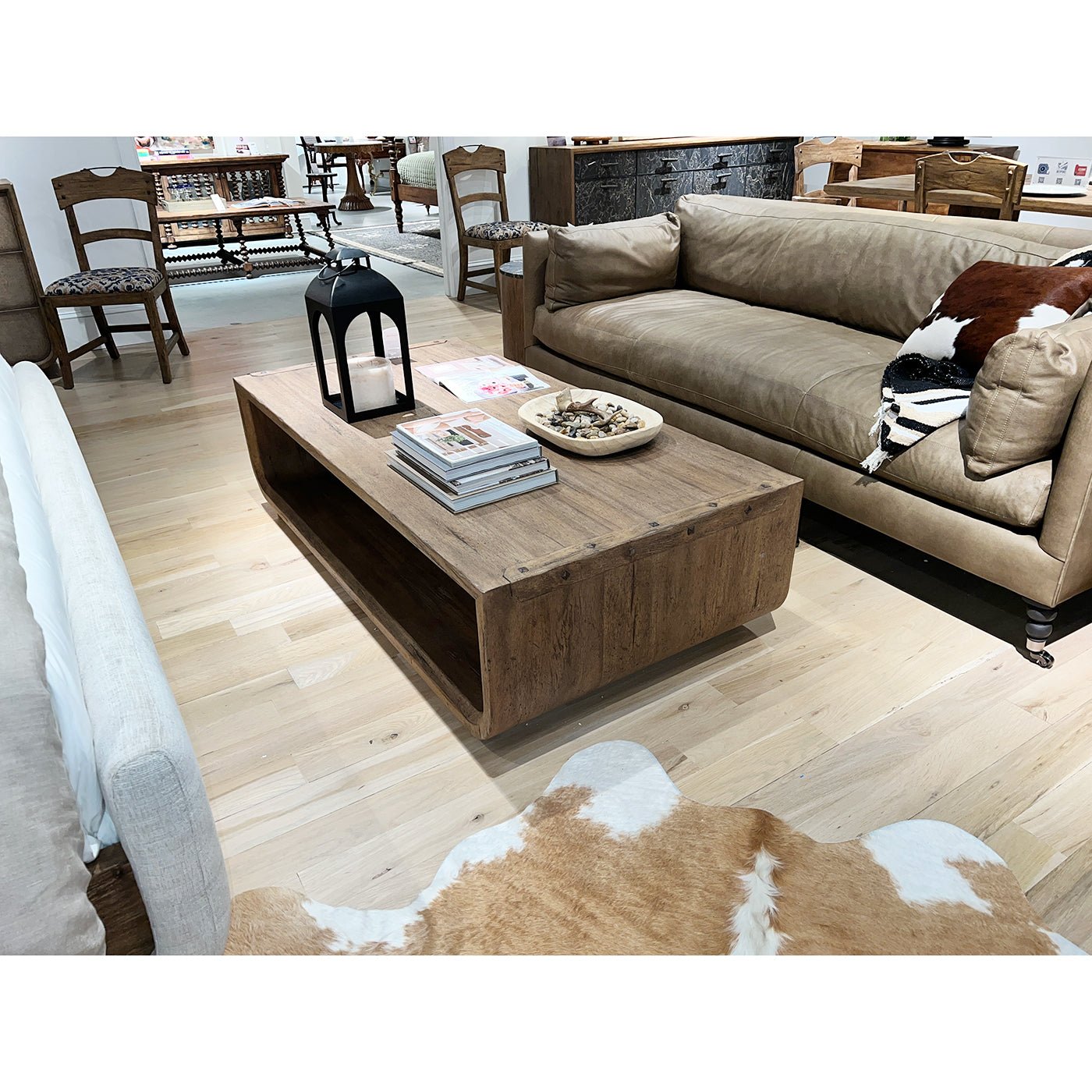 Rustic table with lanterns, beige sofa, and chairs nearby.