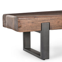 Close-up of the reclaimed wood bench corner showing its thick grained seat and open rectangular iron support