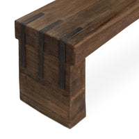 Close-up of the reclaimed wood bench corner showing dark straps joining the thick seat and broad end leg