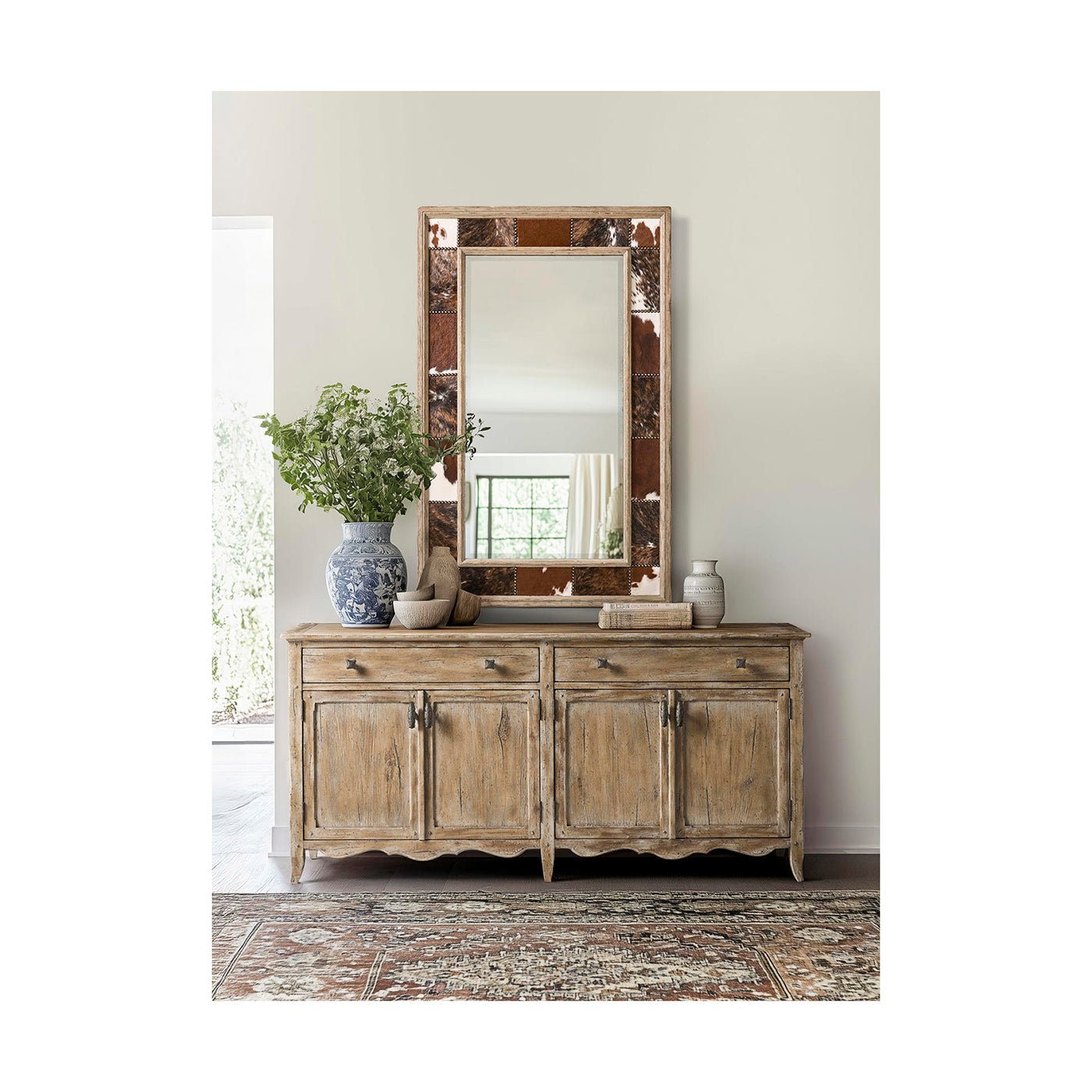 Rustic mirror above wooden cabinet with floral decor.