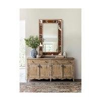 Rustic mirror above wooden cabinet with floral decor.