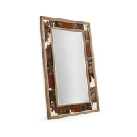 Angled view of rustic cowhide wall mirror.