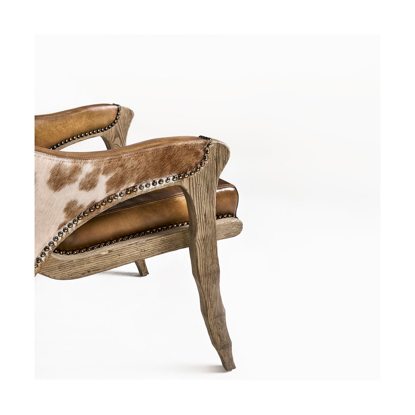Close-up rustic armchair armrest with cowhide and leather.