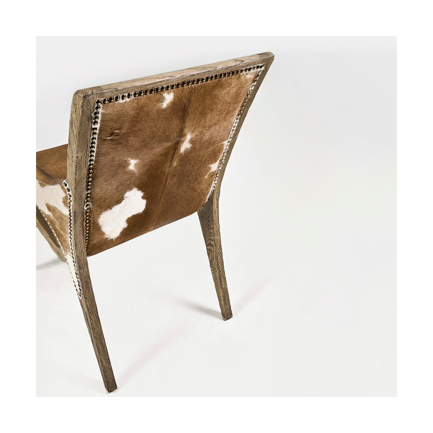 Back view rustic armchair, wooden legs and cowhide.