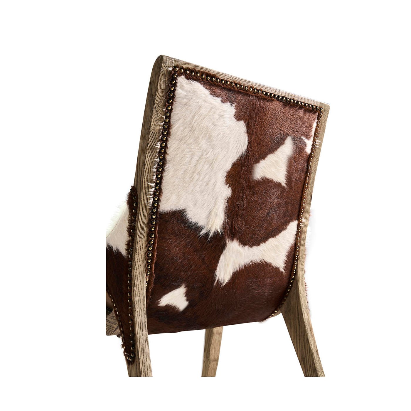 Close-up of rustic chair cowhide upholstery and nailhead detail.
