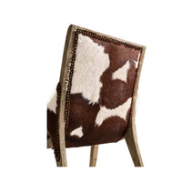Close-up of rustic chair cowhide upholstery and nailhead detail.