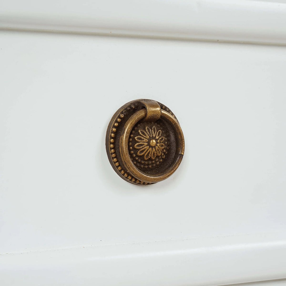 Close-up of ornate handle on nightstand drawer.