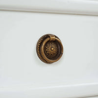 Close-up of ornate handle on nightstand drawer.