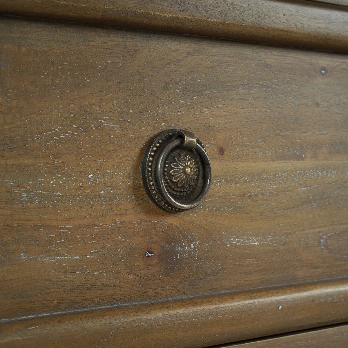 Close-up of handle on rustic wood chest of drawers.