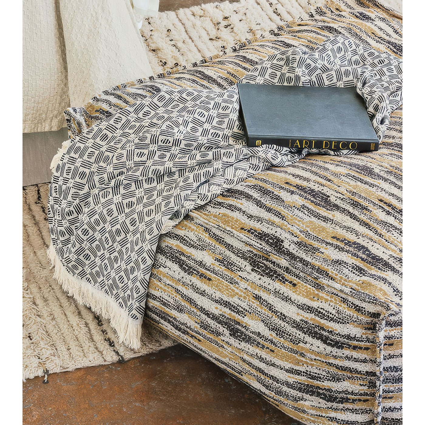 Pouf with blanket and book, cozy setup.