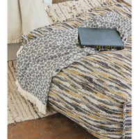Pouf with blanket and book, cozy setup.