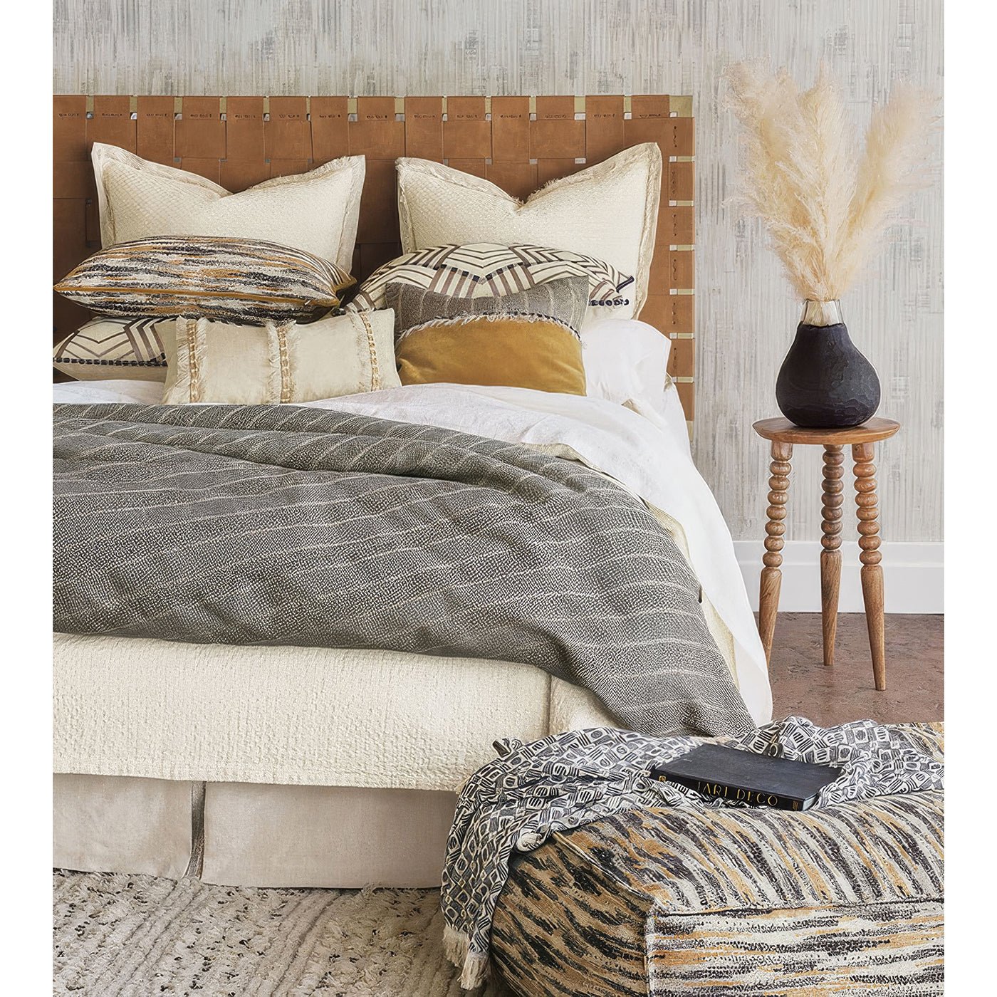 Bedroom setting with pouf and decorative pillows.
