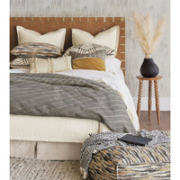 Bedroom setting with pouf and decorative pillows.