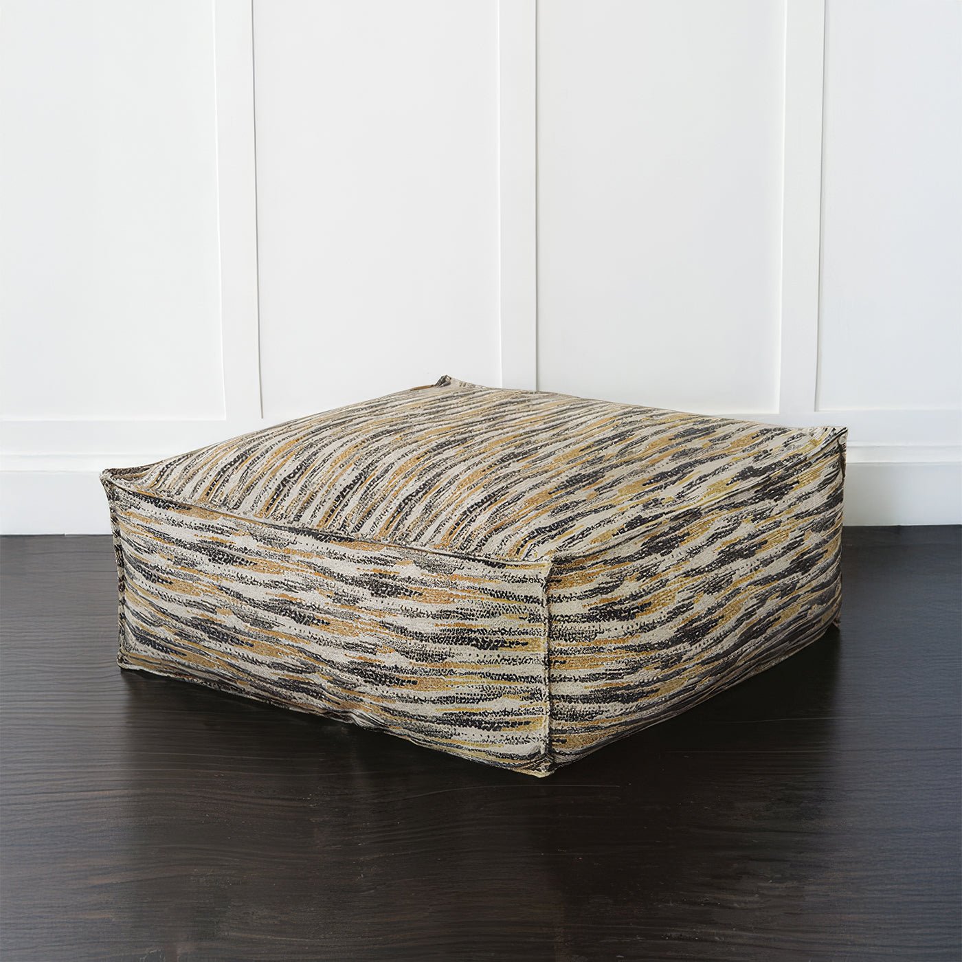 Large floor pouf against white wall, side angle.