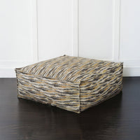 Large floor pouf against white wall, side angle.